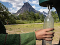 una persona che riempie una bottiglia di acqua potabile da un rubinetto esterno