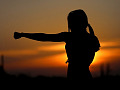 wanita muda berlatih karate di luar pada waktu matahari terbenam