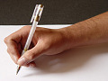 a picture of someone's hand holding a pen over a blank piece of paper