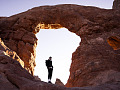 A man standing in a the bright space of an arch amidst rock. Image by Eric Barrett from Pixabay.
