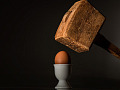 un martillo pesado sostenido sobre un huevo