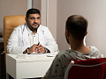ylipainoinen lääkäri puhumassa potilaansa kanssa