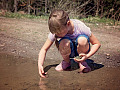 μια νεαρή κοπέλα που κάθεται οκλαδόν και παίζει με τη γη