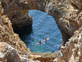 deux kayaks sur l'eau passant sous une arche de pierre