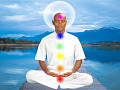 um homem sentado em meditação com os chakras iluminados