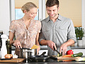 ایک مرد اور عورت باورچی خانے میں ایک ساتھ کھانا بنا رہے ہیں۔