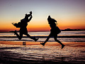 twee mense wat van vreugde op die strand spring
