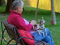 一位白髮女子坐在外面，腿上放著兩隻小狗