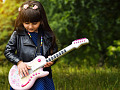 gadis muda dengan bunga di rambutnya bermain gitar elektrik