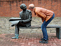 一個男人彎下腰仔細觀察長凳上的雕塑