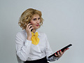 una donna d'affari al telefono con in mano un tablet e sorridente leggermente