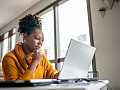 nainen istuu työskentelemässä kannettavalla tietokoneella