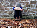 młodzieniec siedzący samotnie na zewnątrz z głową opuszczoną na ramionach