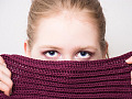 Young woman hiding half of her face behind a knitted cloth. Image by Anemone123 from Pixabay. 