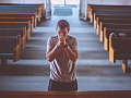 Un uomo inginocchiato in una chiesa che prega. Immagine di Pexels da Pixabay. Dio è bipolare?