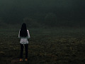 donna in piedi da sola di fronte a un banco di nebbia