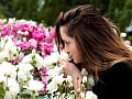 o femeie mirosind un tufiș de trandafiri