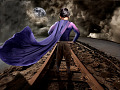 一个身穿超能力斗篷的小男孩站在铁轨上
