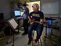 Ung mann spiller gitar mens han har på seg hjelm dekket av elektroder som måler hjerneaktivitet