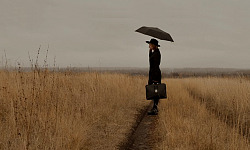 imagen de una mujer en un sendero en un campo abierto y sosteniendo una maleta