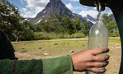 seseorang mengisi ulang botol air minum dari keran luar
