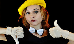 una donna con il trucco da clown che fa il gesto del pollice in su e del pollice in giù