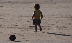 seorang kanak-kanak yang sangat muda bersendirian di pantai