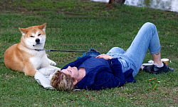 a woman laying back on the grass with her dog