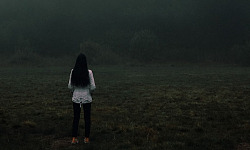 kvinna som står ensam inför en dimbank