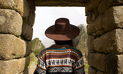 Indiase vrouw staat onder een stenen boog in Machu Picchu