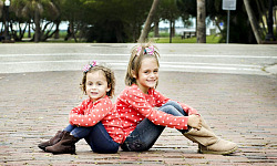 背中合わせに座っている笑顔の 2 人の若い姉妹