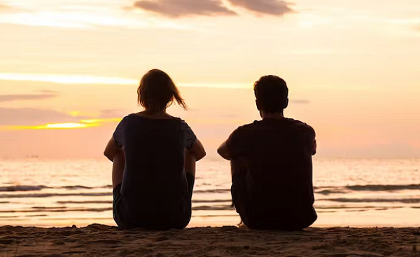 okyanus kenarında oturan iki kişi
