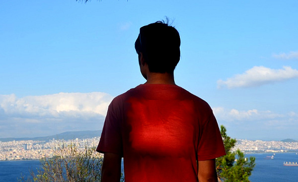 Kalbi ışık saçan genç adam şehre bakan bir tepede duruyor