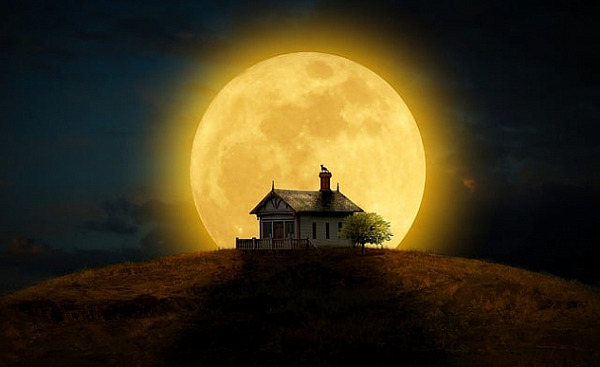 full moon filling the sky behind a house