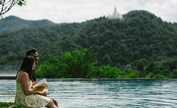 Ein Paar sitzt am Ufer eines Sees und liest ein Buch