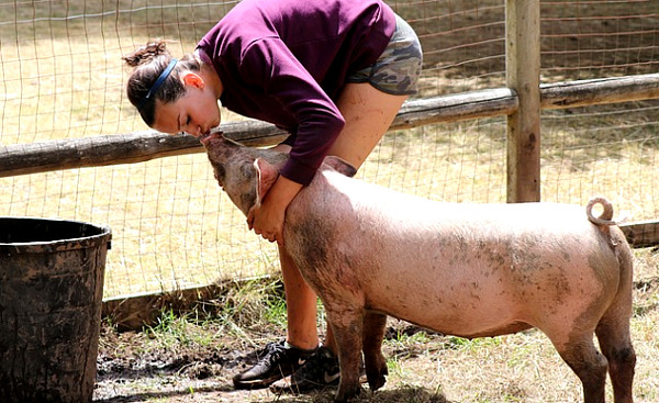 Eine Frau umarmt und streichelt ein Schwein