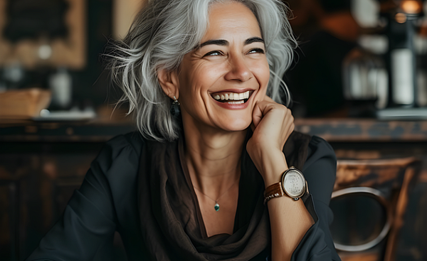 uma mulher tomando uma xícara de café sorrindo radiante para a pessoa que está à sua frente
