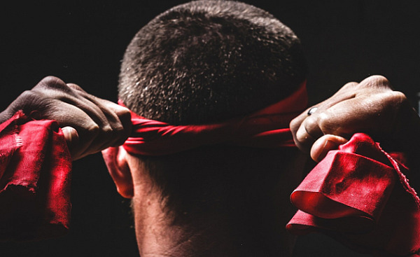 a man tying a blindfold over his eyes