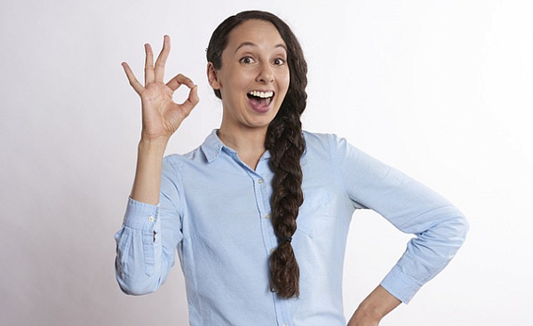wanita dengan senyuman lebar dan jari dalam simbol "a-ok".