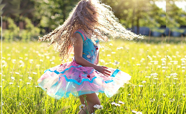 young girl dancing and twirling outside in a meadow