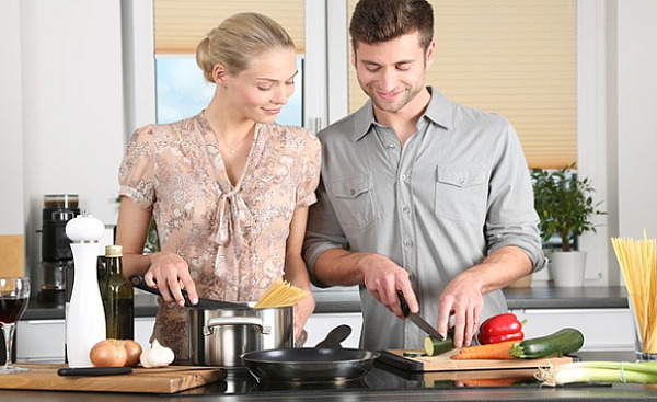um homem e uma mulher preparando comida juntos na cozinha
