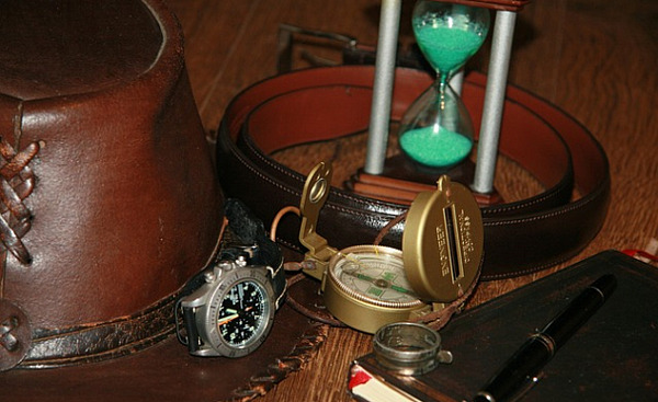 eine Sanduhr, ein Kompass, ein Stift und ein Notizbuch