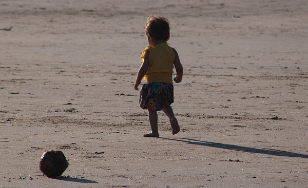 समुद्र तट पर एक बहुत छोटा बच्चा अकेला