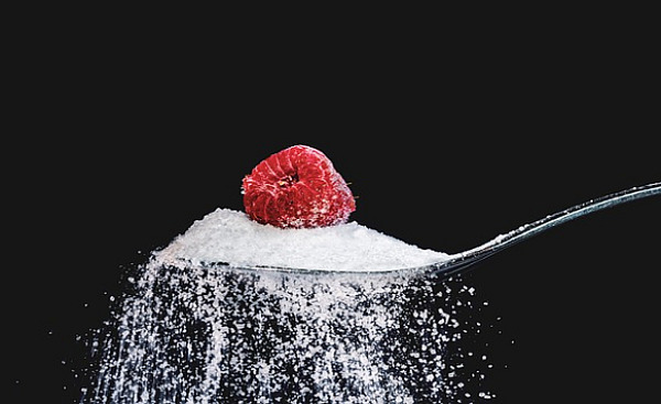 یک تمشک روی یک قاشق چایخوری شکر نشسته است