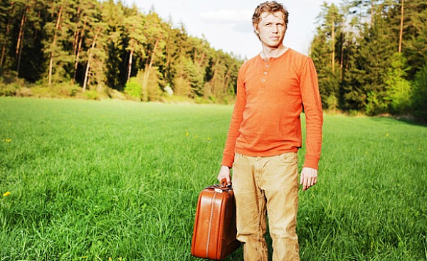 uomo in piedi da solo con in mano una valigia