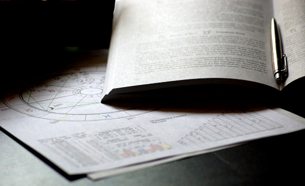 bir astroloji haritası, açık bir kitap ve bir kalem