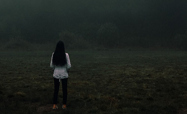زنی که به تنهایی روبه‌روی ساحلی از مه ایستاده است