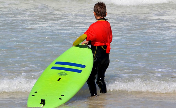 바디 서핑 보드를 들고 바다 가장자리에 서있는 아이