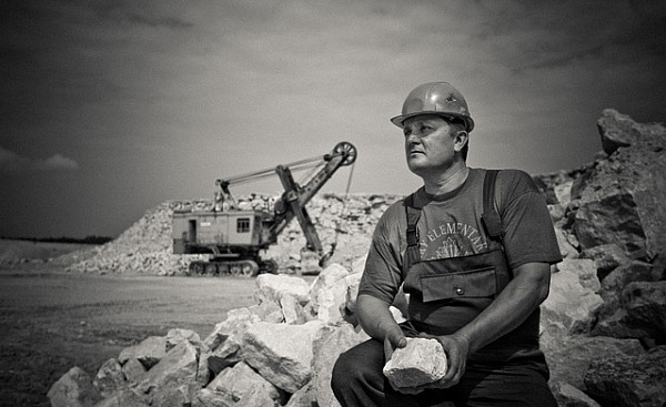 Mann sitzt mit einem großen Stein auf einer Baustelle