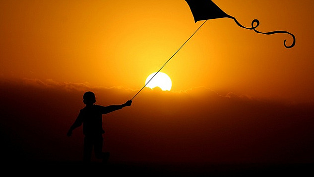 a child flying a kite under the bright shining sun